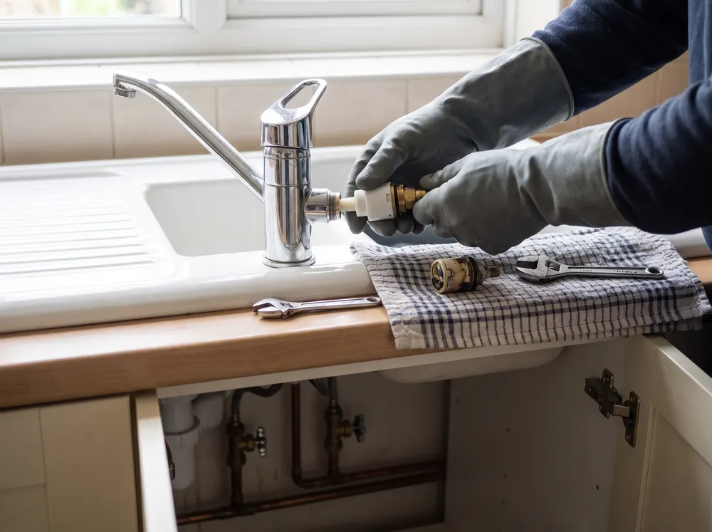 Mãos de canalizador a trocar o cartucho de uma misturadora de cozinha